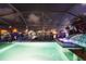 Evening view of backyard pool, lit by underwater lights, waterfront, and tropical foliage at 6601 Nautical Isle, Hudson, FL 34667