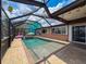 Bright and airy screened pool area with a charming flamingo float, complemented by a seating area for relaxation at 6601 Nautical Isle, Hudson, FL 34667