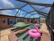 Charming screened pool area with playful flamingo float and umbrella table, perfect for sunny relaxation at 6601 Nautical Isle, Hudson, FL 34667