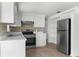 Kitchen with white cabinetry, mosaic backsplash, stainless steel appliances, and neutral tile flooring at 6633 Jackson St, New Port Richey, FL 34653