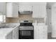 Well-lit kitchen featuring white cabinetry, stainless steel appliances, and a stylish mosaic backsplash at 6633 Jackson St, New Port Richey, FL 34653