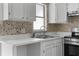 Bright kitchen boasts white cabinets, neutral countertops, stainless steel oven, and mosaic backsplash at 6633 Jackson St, New Port Richey, FL 34653