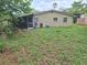 Backyard featuring a screened-in patio and ample yard space ready for landscaping design at 7100 Ashwood Dr, Port Richey, FL 34668