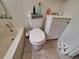 Bathroom with a toilet, sink, and shower-tub combo with a white tile surround at 7100 Ashwood Dr, Port Richey, FL 34668
