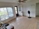 Neutral living room featuring tile flooring and a ceiling fan, brightened by natural light from large windows at 7100 Ashwood Dr, Port Richey, FL 34668