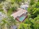 Aerial view of a private screened-in pool surrounded by lush greenery and mature trees at 7119 Lenape Cir, New Port Richey, FL 34653