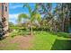The home features a sprawling green lawn with a palm tree and views of mature trees in a private backyard setting at 7340 Brightwaters Ct, New Port Richey, FL 34652