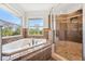 Bright bathroom featuring tub and glass door shower with a view of natural landscape at 7340 Brightwaters Ct, New Port Richey, FL 34652