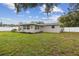 A sprawling backyard features lush green grass, mature trees, and a pristine white fence at 7545 Banner St, New Port Richey, FL 34653