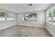 Bright bedroom featuring three windows, gray tile floors, and neutral paint at 7545 Banner St, New Port Richey, FL 34653
