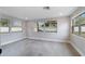 Bright bedroom featuring three windows, gray tile floors, and neutral paint at 7545 Banner St, New Port Richey, FL 34653