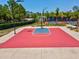 Outdoor basketball court with a red and blue painted surface near lush green trees at 8248 Sugarbush Dr, Spring Hill, FL 34606
