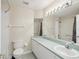 Bright bathroom featuring a long vanity with a sink, a toilet, a mirror and a shower at 8248 Sugarbush Dr, Spring Hill, FL 34606