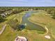 Aerial view of a lush golf course with mature trees, a winding water feature, and meticulously manicured greens at 8248 Sugarbush Dr, Spring Hill, FL 34606