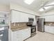 Bright kitchen with stainless appliances, granite countertops, white cabinets, and tile flooring at 8248 Sugarbush Dr, Spring Hill, FL 34606