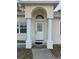 Elegant front entrance with decorative glass door, flanked by white columns supporting a unique arched entry at 8291 Weeping Willow St, Brooksville, FL 34613