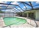 Screened-in pool with stone patio, palm trees, and backyard at 10277 Rosetti Ct, Spring Hill, FL 34608