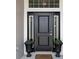 A welcoming black front door is flanked by decorative planters, creating a charming entry at 11042 Heth Ct, Weeki Wachee, FL 34613