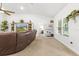 Bright living room boasts a brown leather sofa, light-colored carpet, and a decorative bookshelf at 11042 Heth Ct, Weeki Wachee, FL 34613