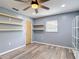 Bright bedroom with ceiling fan, built-in shelves, and wood-look flooring at 11340 Corinthian St, Spring Hill, FL 34609
