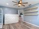 Bedroom featuring ceiling fan, wood-look floors, shelving, and open doorway at 11340 Corinthian St, Spring Hill, FL 34609