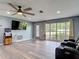 Living room featuring wood-look floors, ceiling fan, and a bright window overlooking the front yard at 11340 Corinthian St, Spring Hill, FL 34609