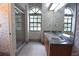 Charming bathroom with floral wallpaper, tiled floor, double sinks, arched window, and a walk-in shower at 11364 Orangewood Ct, Spring Hill, FL 34609