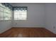 A bright bedroom features hardwood floors, white walls, and windows with sheer curtains at 11364 Orangewood Ct, Spring Hill, FL 34609
