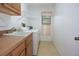 A laundry room with a washing machine, sink, cabinets, and a window with a pink curtain at 11364 Orangewood Ct, Spring Hill, FL 34609