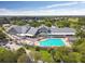 Aerial shot of a community pool, hot tub, and clubhouse nestled among lush greenery at 11637 Spindrift Loop, Hudson, FL 34667