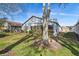 Backyard with an angled view of the house behind a tree in a grassy yard at 11637 Spindrift Loop, Hudson, FL 34667