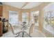 Bright breakfast nook featuring a glass table, white chairs, and a view from the multiple windows at 11637 Spindrift Loop, Hudson, FL 34667