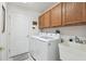 Laundry room with modern washer and dryer, utility sink, and storage cabinets at 11637 Spindrift Loop, Hudson, FL 34667