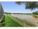 An expansive backyard with green grass, a white picket fence, and beautiful lake views beyond, perfect for relaxation at 1236 Ketzal Dr, Trinity, FL 34655