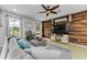 Cozy living room featuring a wood accent wall, large windows, a comfortable sectional sofa, and a ceiling fan at 1236 Ketzal Dr, Trinity, FL 34655