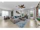 Open-concept living room with a large sectional sofa, tile flooring, ceiling fan, and views of the backyard at 1236 Ketzal Dr, Trinity, FL 34655