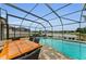 A beautiful screened-in pool with a dining table, basketball hoop, and lake views at 1236 Ketzal Dr, Trinity, FL 34655