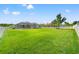 Large backyard with manicured lawn, white picket fence, picnic table, and screened-in pool at 13627 Lightning Rod Ct, Hudson, FL 34669