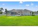 Rear exterior of home with a large manicured lawn, screened-in pool, and white picket fence surround at 13627 Lightning Rod Ct, Hudson, FL 34669