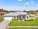 Inviting single-story home featuring a manicured lawn, charming landscaping, and an attached two-car garage at 13627 Lightning Rod Ct, Hudson, FL 34669