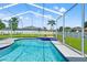 A view of the backyard screened-in pool and deck with a green inflatable in the pool at 13627 Lightning Rod Ct, Hudson, FL 34669