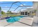 Screened in pool with a tile waterfall feature, stamped concrete decking, and well-maintained lawn beyond at 13627 Lightning Rod Ct, Hudson, FL 34669