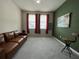 Cozy living room with brown leather couch, grey carpet and natural light from the windows at 1508 Figleaf Ln, Clearwater, FL 33756