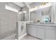 Modern bathroom featuring a large glass shower, gray tiled walls and cabinets, and double sink at 15241 Caravan Ave, Odessa, FL 33556