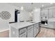 Bright kitchen island featuring quartz countertops, seating, modern fixtures, and grey cabinets with stainless appliances at 15241 Caravan Ave, Odessa, FL 33556