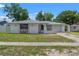 Charming single-story home featuring stone accents, a gray roof, and mature trees in a suburban neighborhood at 16018 Adobe Dr, Hudson, FL 34667