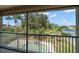 View from a screened balcony overlooking a pool and tropical landscaping with a lake beyond at 17905 Machair Ln, Land O Lakes, FL 34638