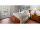 This bright bedroom features hardwood floors, a queen bed, a large window, and a door that leads to a balcony at 17905 Machair Ln, Land O Lakes, FL 34638