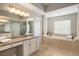 This large bath features dual vanities, columns, a jetted tub, a walk-in shower, and lots of natural light at 17905 Machair Ln, Land O Lakes, FL 34638