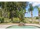 Backyard pool and landscaping featuring a small waterfall near a scenic pond and mature trees at 17905 Machair Ln, Land O Lakes, FL 34638